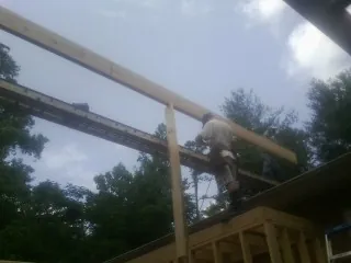 Carpenter setting a ridge beam over a new addition frame — Ice Dam Removal by Roofing Brothers in Mcleod