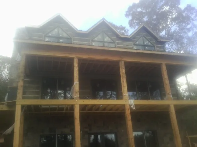 Dormers and porch framing on a large log home under construction — Roof Coating work by our crew in Mcleod