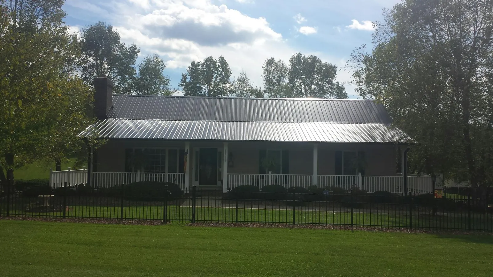 Gray metal roof on a brick ranch with a full width front porch — Gutter Guard Installation work by our crew in Mcleod
